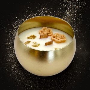 Bougie artisanale MURI dans un contenant doré mat, décorée de deux roses en cire et d’une mèche en bois centrale