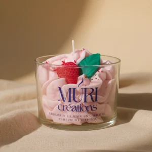 Bougie parfumée à la fraise de la marque artisanale Muri Créations, avec cire fouettée rose effet chantilly décorée d'une fraise et d'une feuille verte, coulée à la main en Lorraine.