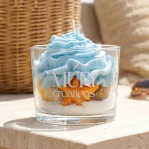 Bougie artisanale gourmande Brise Marine de la marque Muri Créations, collection printemps-été 2026. Bougie décorative en verre avec cire effet sable, étoile de mer orange et topping chantilly bleu océan.