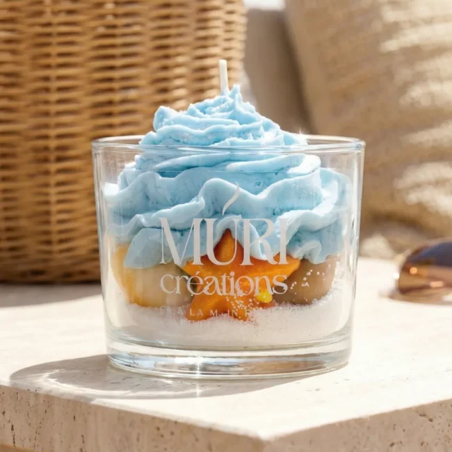 Boutique - Bougies Artisanales - Muri Créations 9 Bougie artisanale gourmande Brise Marine de la marque Muri Créations, collection printemps-été 2026. Bougie décorative en verre avec cire effet sable, étoile de mer orange et topping chantilly bleu océan.
