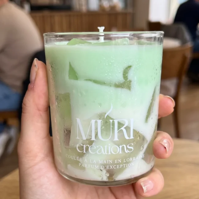Bougie artisanale trompe-l'oeil Ice Latte Pistache par Muri Créations tenue en main. Bougie gourmande verte avec effet glaçons réaliste coulée à la main en Lorraine, issue de la même collection que la bougie Sex on the Beach.